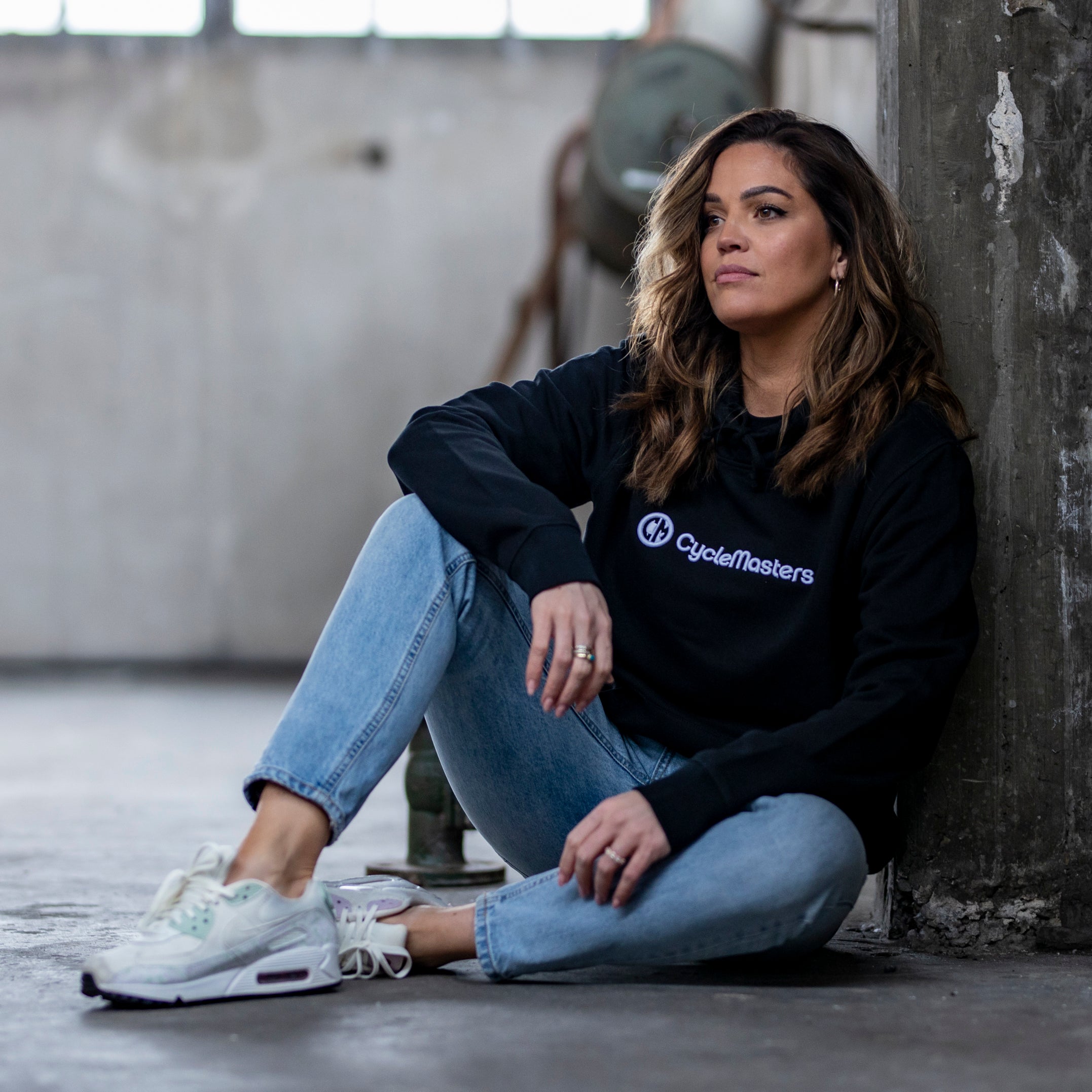 A woman wears a black CycleMasters hoodie