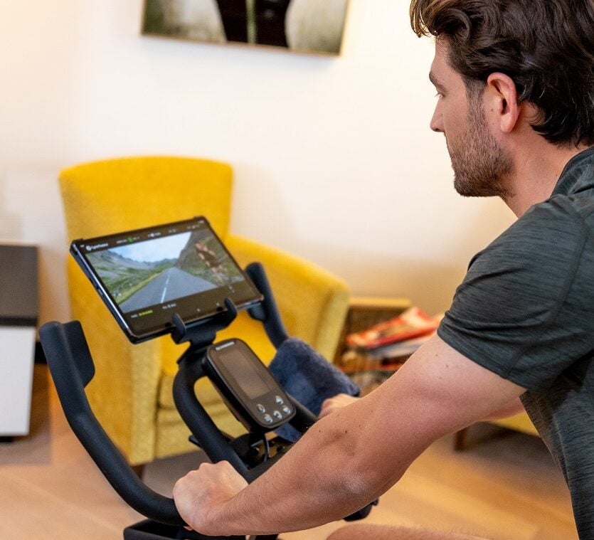 A man follows his Indoor Cycling Workouts on his spinning bike